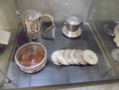A silver plate jug, wine coaster, 6 drinks coasters and one other item.
