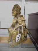 A brass seated figure of an elderly lady.
