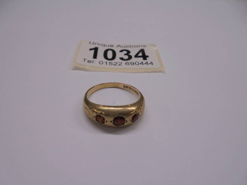 A 9ct gold three stone garnet ring, size P, 3.15 grams.