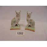 A pair of continental porcelain cats on cushions, 10 cm tall.