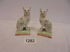 A pair of continental porcelain cats on cushions, 10 cm tall.