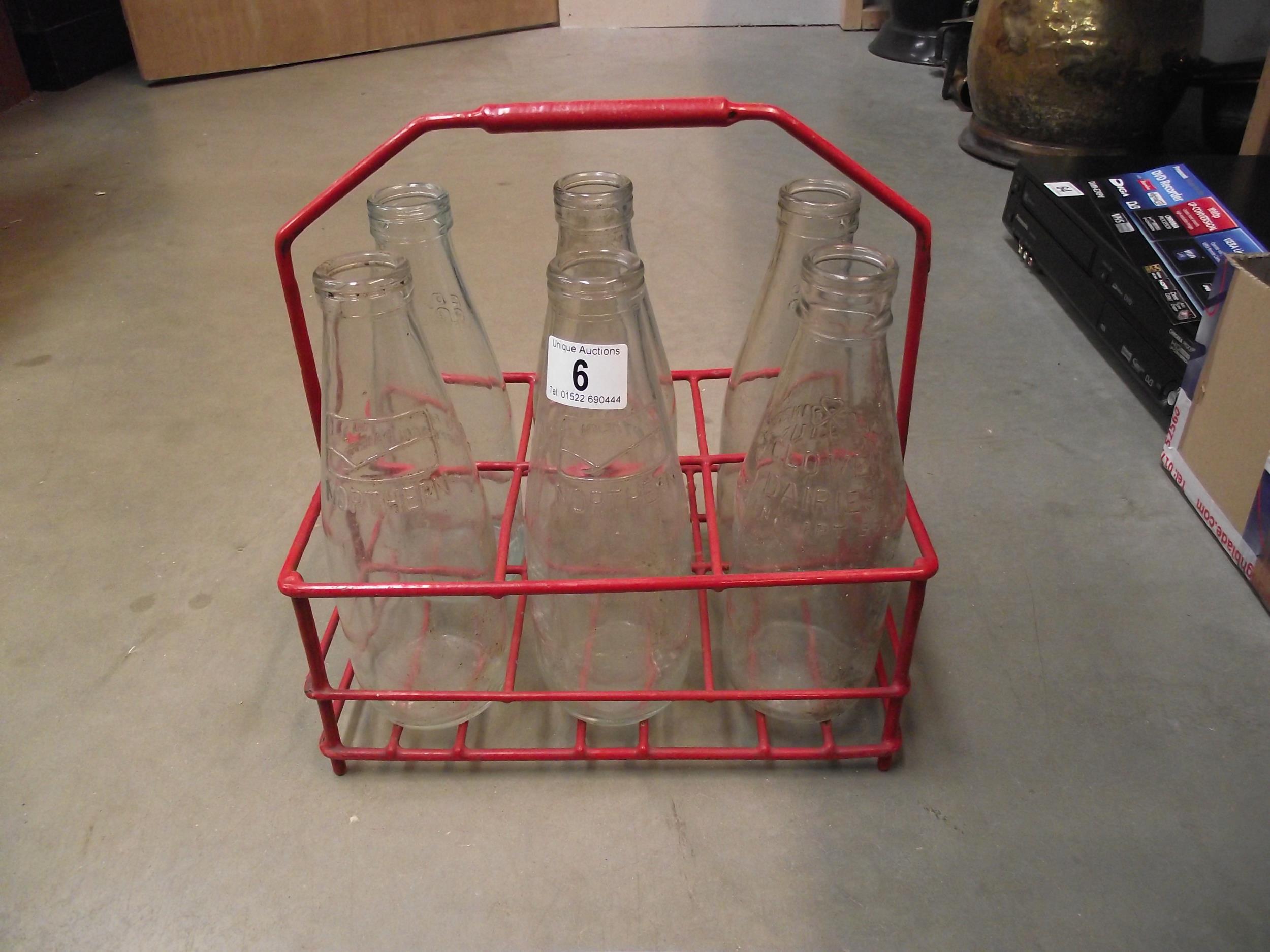 A vintage milkmans bottle basket with 6 vintage 1 pint glass milk bottles, 3 of which are Co-op, 2