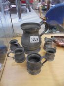 A large old pewter tankard and five miniature pewter tankards.