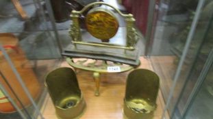 A brass trivet, brass gong and two brass candleholders.