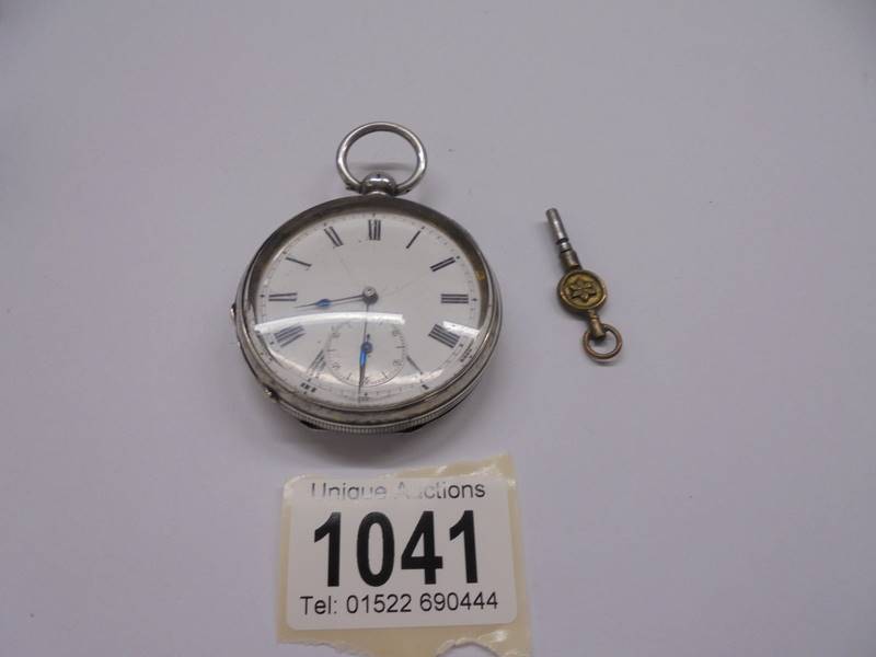 A silver pocket watch with key, in working order.