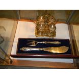 A cased pair of silver plate fish servers and a silver plate egg cup stand.