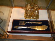 A cased pair of silver plate fish servers and a silver plate egg cup stand.