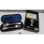 A cased silver christening egg cup with spoons and a cased silver spoon and fork set.