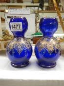 A pair of blue glass vases with gilded decoration.