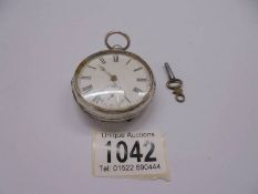 A silver pocket watch with key, in working order.