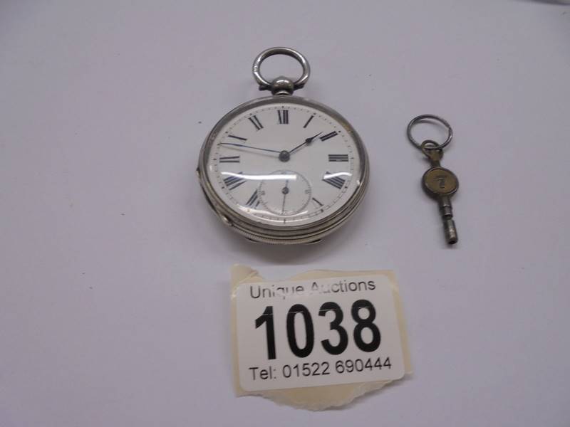 A silver pocket watch with key, in working order.
