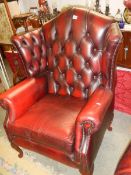 A red leather wing armchair. COLLECT ONLY.