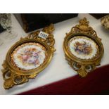 A pair of ceramic plates in metal frames.