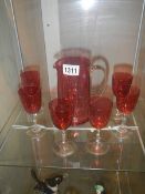 A Cranberry glass jug and six goblets.