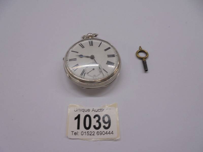 A silver pocket watch with key, in working order.