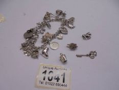 A silver charm bracelet with padlock and 22 charms (2 marked 925, others not marked) and 4 charms.