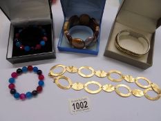 Four contemporary bracelets and a necklace.