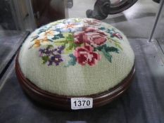 A circular mahogany foot stool with tapestry top.