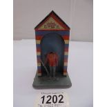 A vintage tin plate sentry box tin money box, (figure missing head), 11 cm tall.