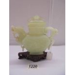 An oriental carved jade teapot on stand.