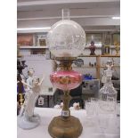 A Victorian oil lamp on a brass base with a handpainted pink glass font and acid etched shade,