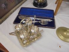 A silver plate egg cup stand with spoons (M & Co.,) and a cased pair of silver plate fish servers.