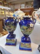 A pair of Victorian blue ceramic urns featuring village scenes, COLLECT ONLY.