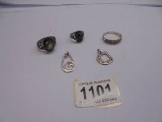 Three silver rings and two silver pendants.