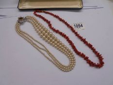 A three strand pearl necklace and a coral necklace.