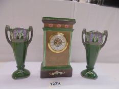A ceramic three piece clock garniture with quartz movement, clock 20 cm, side pieces 17 cm.