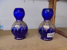 A pair of hand decorated blue glass vases. 16.5cm.