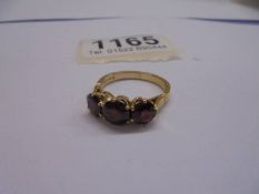 A 750 (18ct) gold ring set three garnets, size O, total weight 4.37 grams.