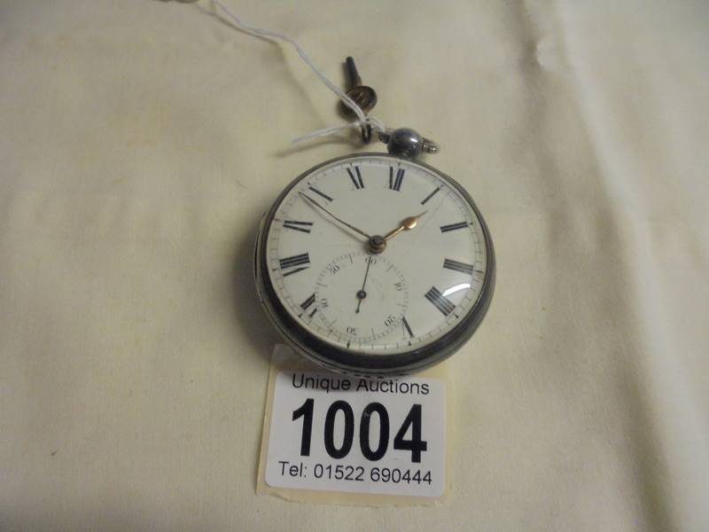 A silver pocket watch with key, dial cracked and not working.