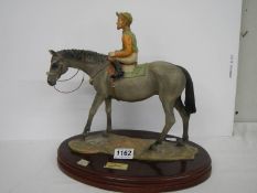 A horse with jockey figure on a wooden base.