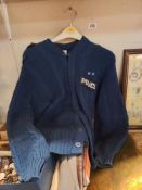 A knitted dark blue cardigan with sewn on police insignia