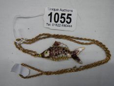 A mid 20th century enamel articulated fish pendant on yellow metal chain.