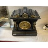 A black slate mantel clock with figural pillars either side of face