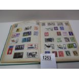 A green stamp album with several incomplete pages of stamps from around the world.