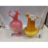 An antique yellow satin galss jug, 16 cm tall and an antique pink glass jug with applied flower,