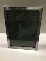 A silver framed picture frame stamped MV on frame