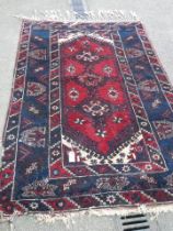 A good old rug in a blue and red pattern, 76 x 50 inches. COLLECT ONLY.
