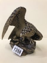 A stoneware pottery figure of a bird of prey fighting a snake