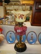 A Victorian oil lamp with cranberry glass font and original shade, COLLECT ONLY.