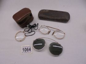 A vintage gilded monacle eye piece, clip on sunglasses and one other.