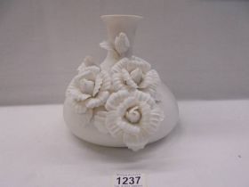 A white ceramic vase with applied roses.