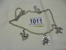 A long silver chain with three silver charms,