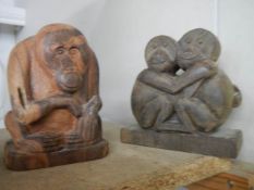 A carved wood figure of an orangutan and another carved ape figure.