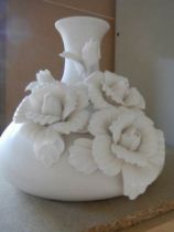 A white bulbous shaped vase with applied roses.