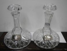 a pair of cut glass decanters with silver brandy and whisky labels.