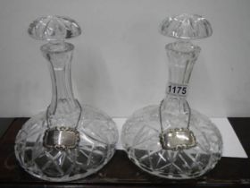 a pair of cut glass decanters with silver brandy and whisky labels.